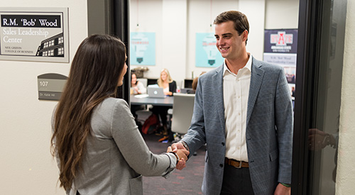 A student is greeted at the door of the sales center on campus